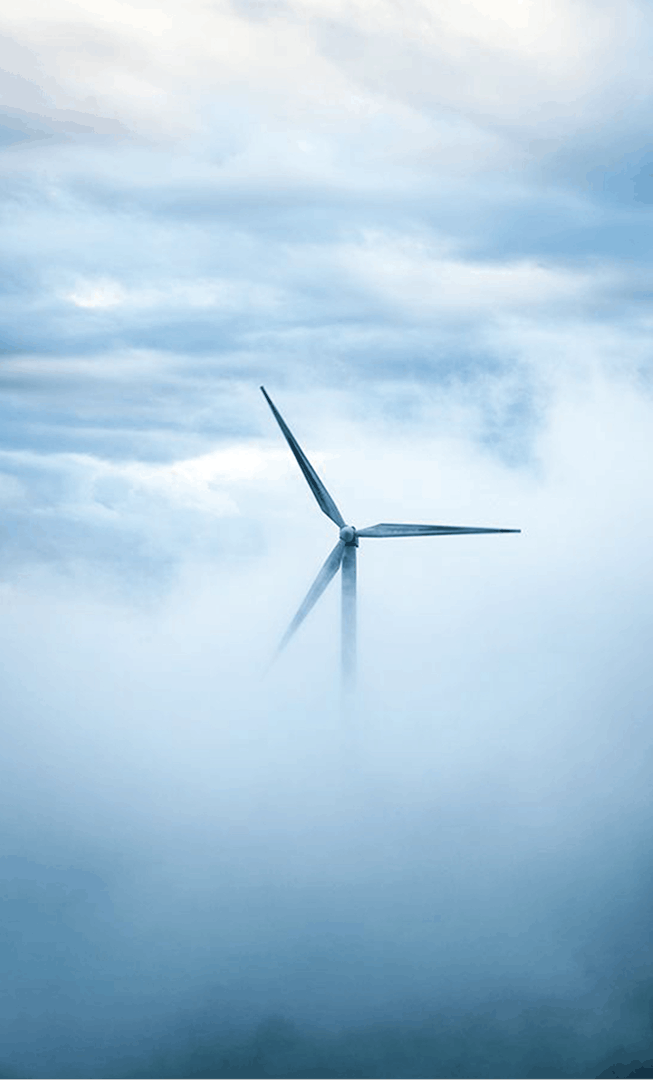 Tall wind turbine rising through clouds